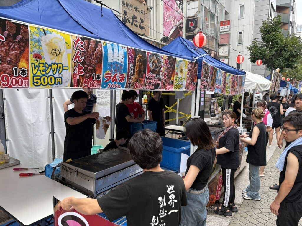 提灯が並ぶ麻布十番祭りの屋台とスタッフ