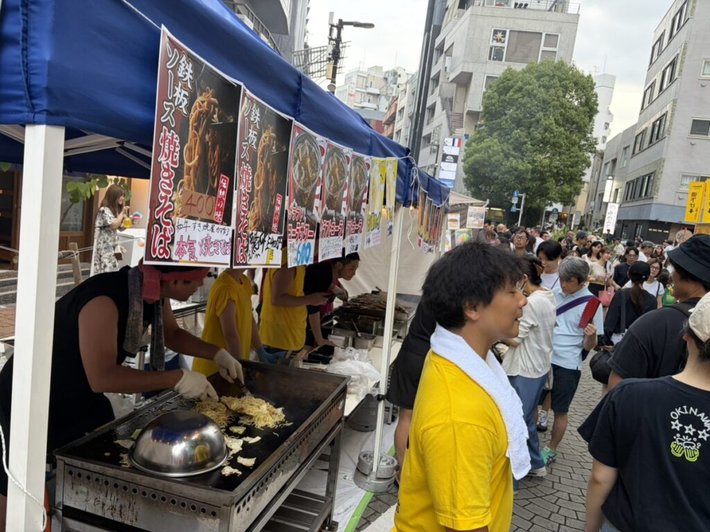 行列のそばで焼きそばを調理するスタッフ